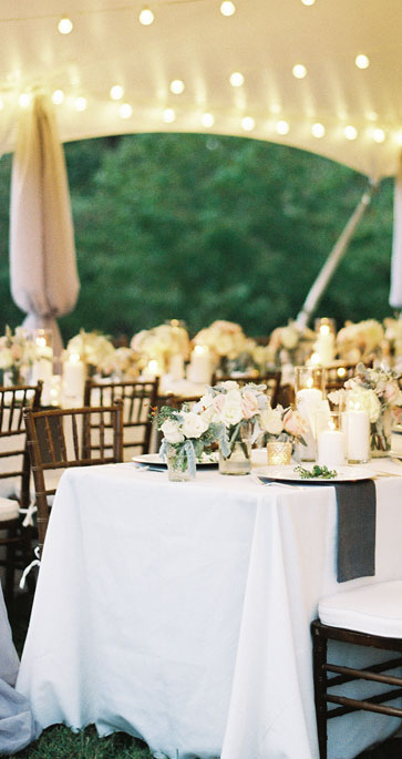 Reception tables set under the tent lights