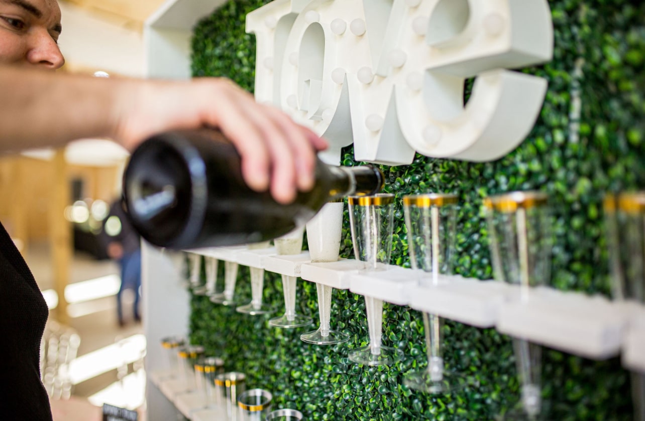 Champagne poured into flutes on the boxwood love wall